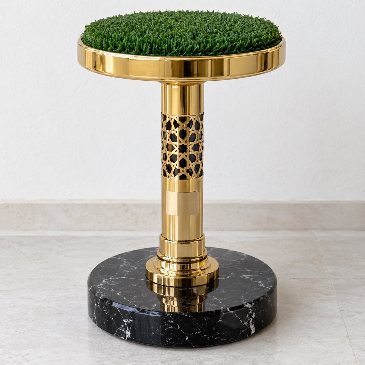 Gold falcon perch wakir with green turf top, gold geometric column and black marble base against a white wall