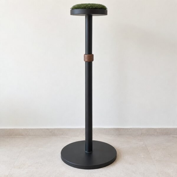 Tall matte black and walnut falcon perch with round turf top and steel base on a light floor