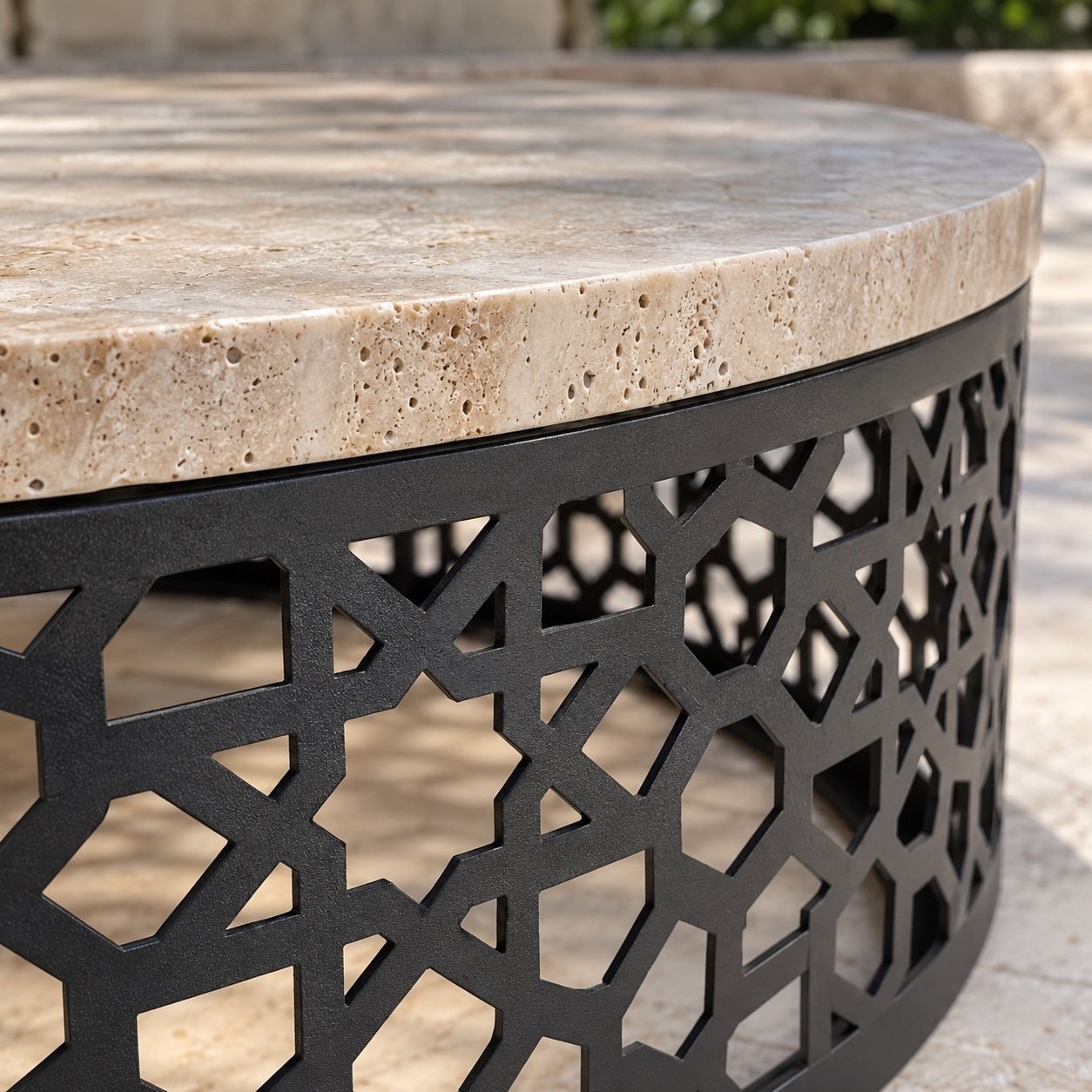 Close-up of natural beige travertine edge and black powder-coated laser-cut geometric steel base