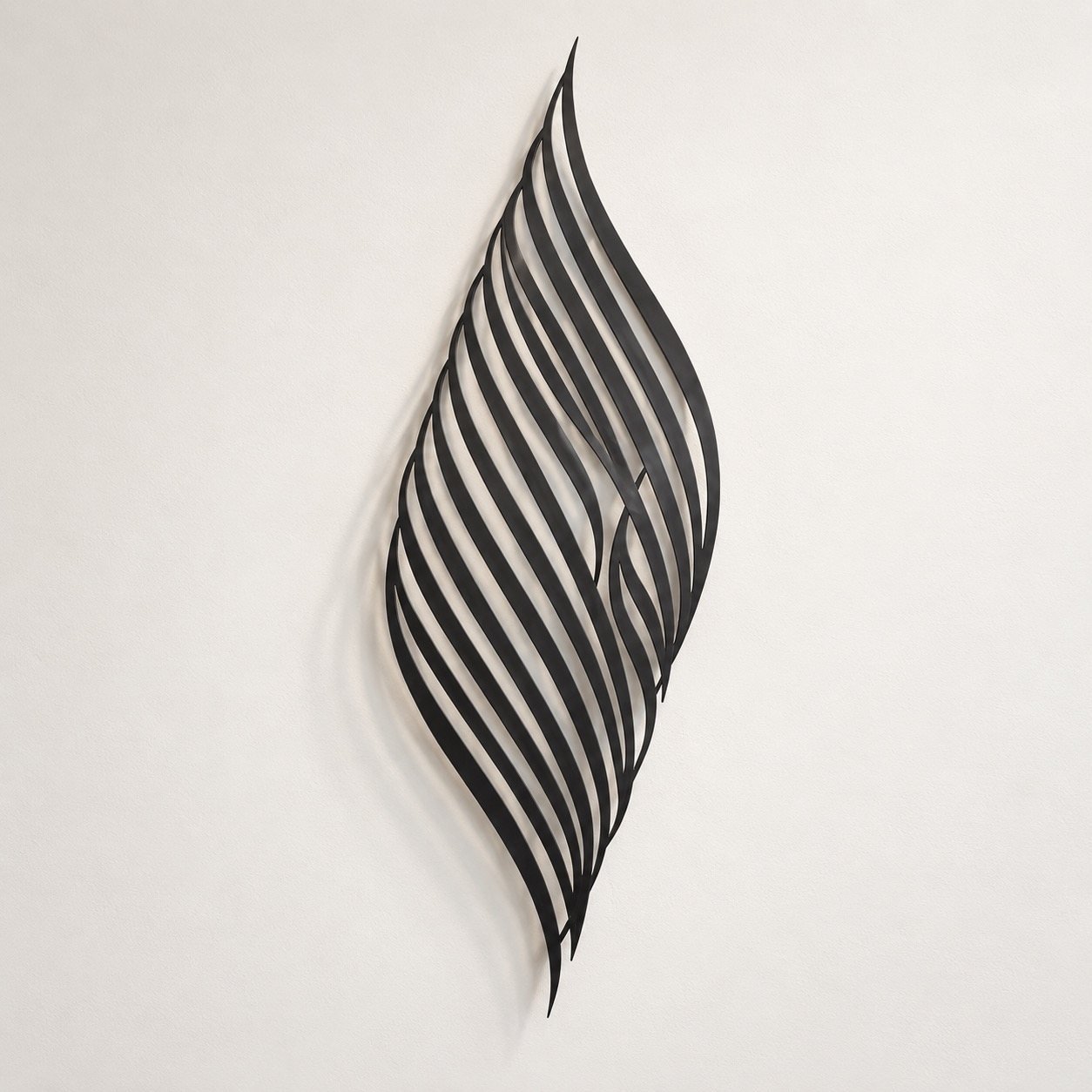 Black single-piece La Elah Ela Allah metal wall art on a plain warm-white wall