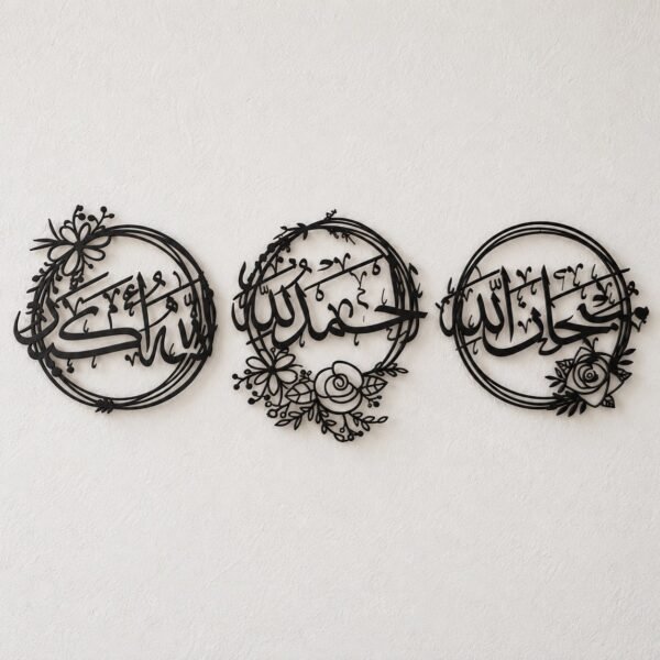 Three-piece black metal Arabic calligraphy wall art set on a plain warm-white wall.