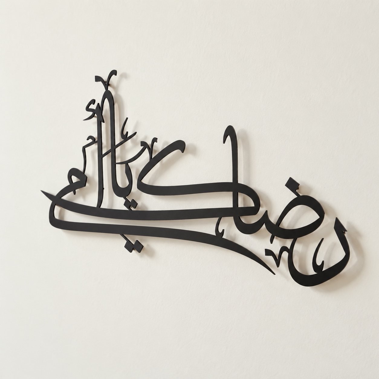 Angled view of matte black Arabic calligraphy wall art showing its cut-out depth, edge finish and wall shadow.