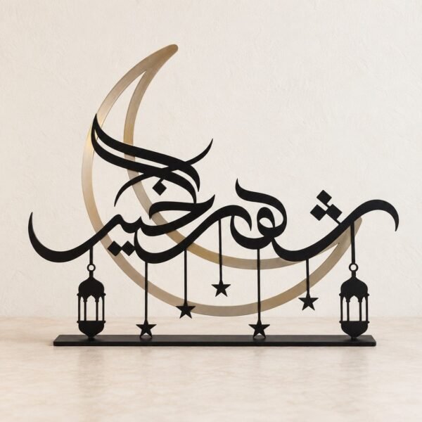 Black Ramadan crescent metal tabletop decoration with Arabic calligraphy on a plain warm-white wall