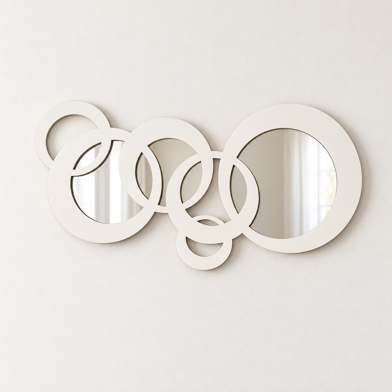 Circles Wall Mirror with interlocking white round frames on a plain warm-white wall, front view.