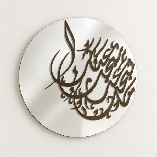 Round silver wall mirror with dark raised Arabic calligraphy on a warm-white wall