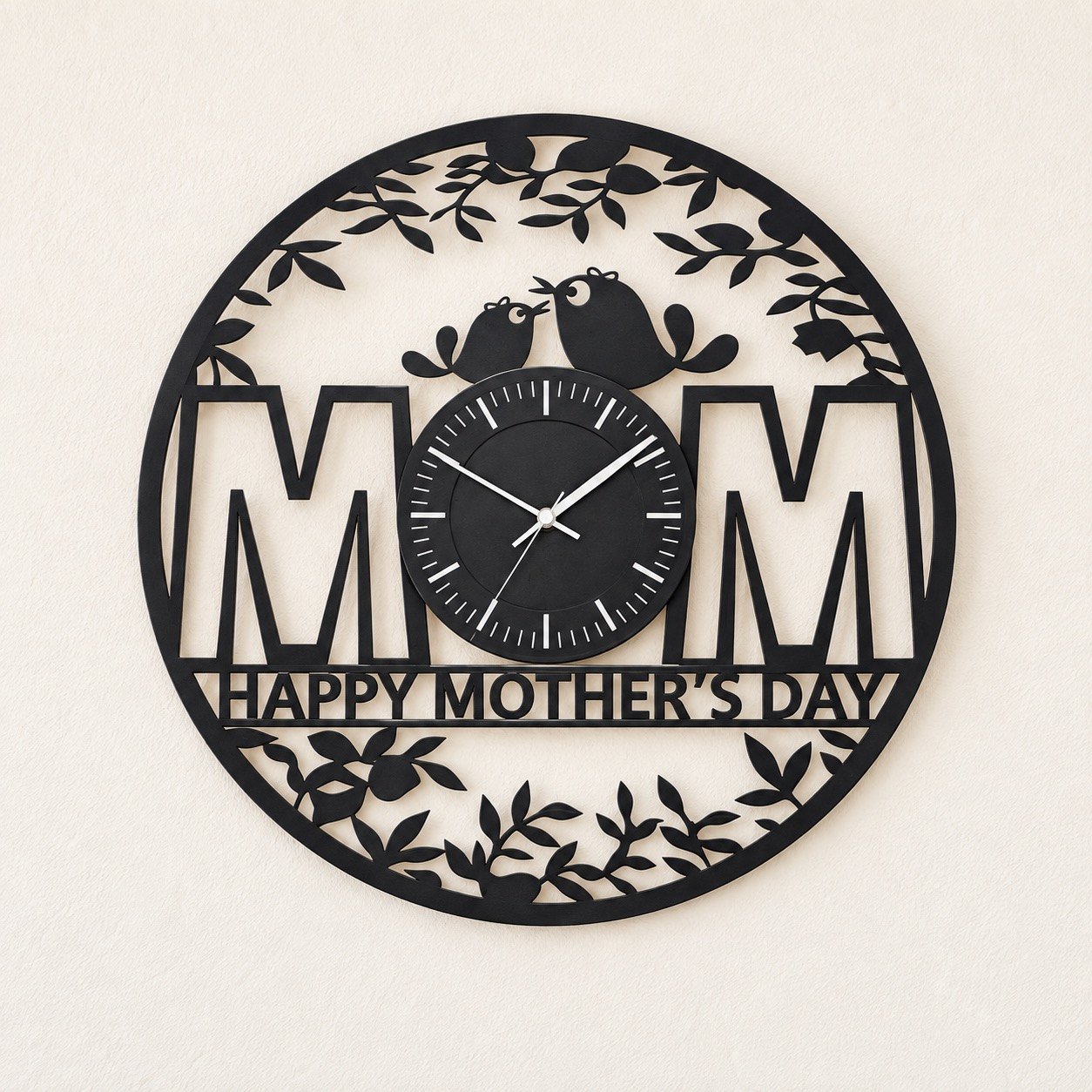 Black round Mothers Day metal wall clock on a plain warm-white wall, front view.