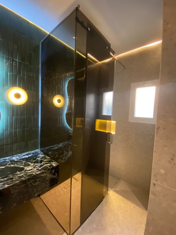 Smoked grey glass sliding shower enclosure fitted in a modern UAE villa bathroom