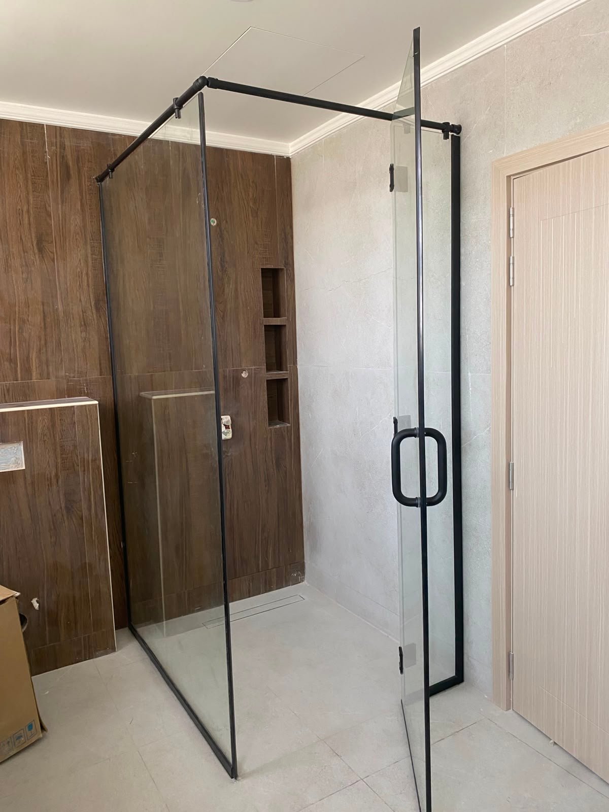 Black frame shower against wood-look wall